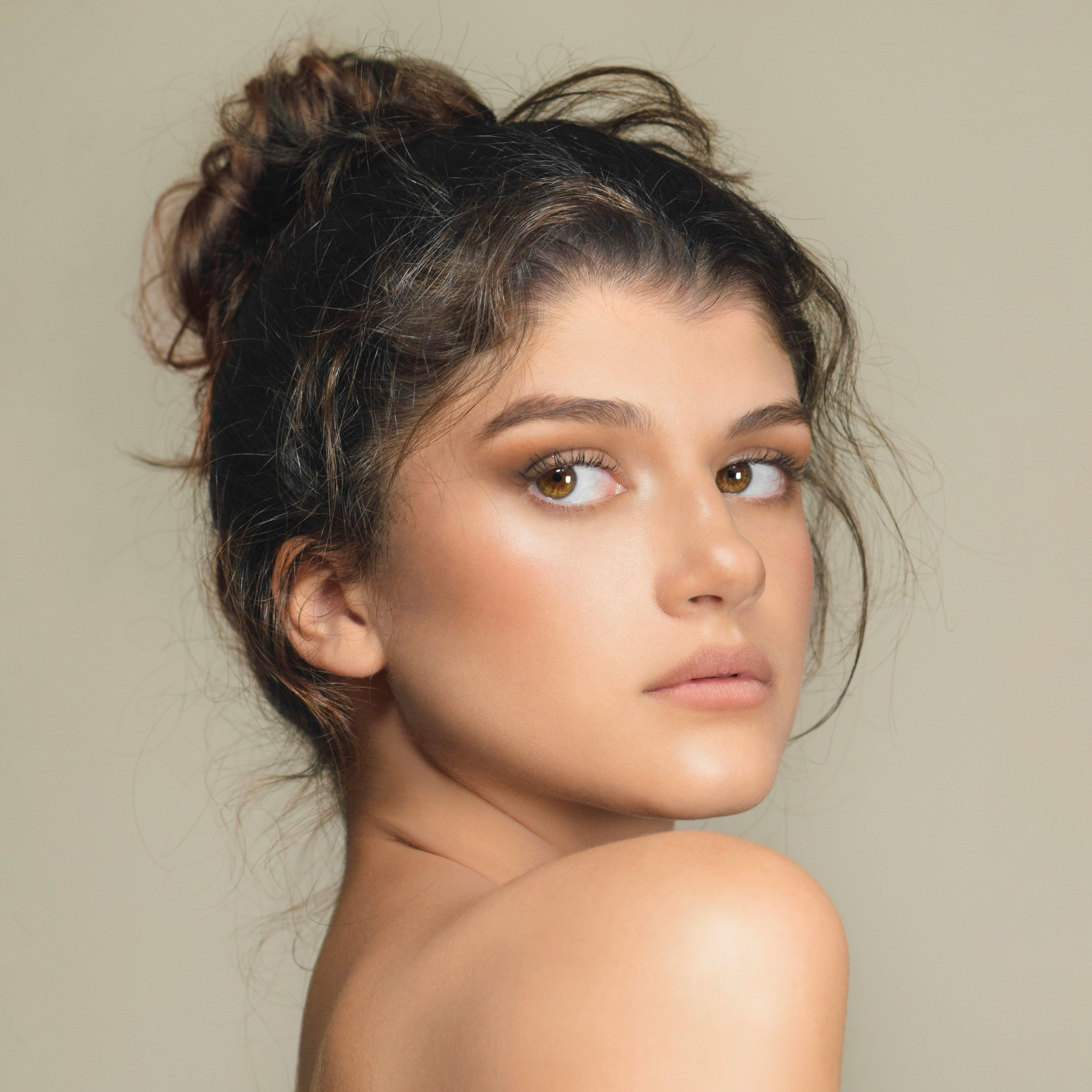 Kaers Woman with a stylish hair bun against a neutral background