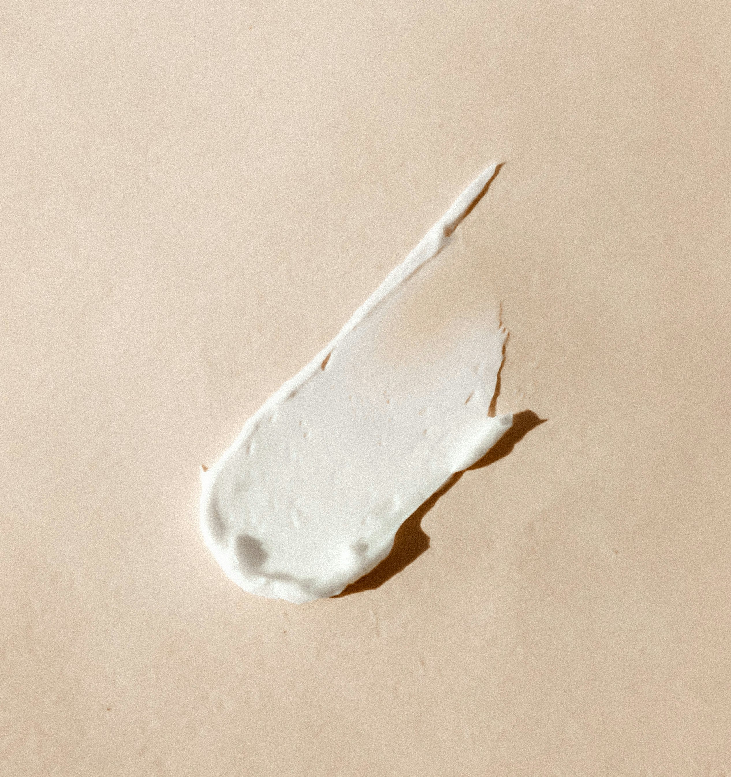 White cream smear on a beige background - kaers body milk